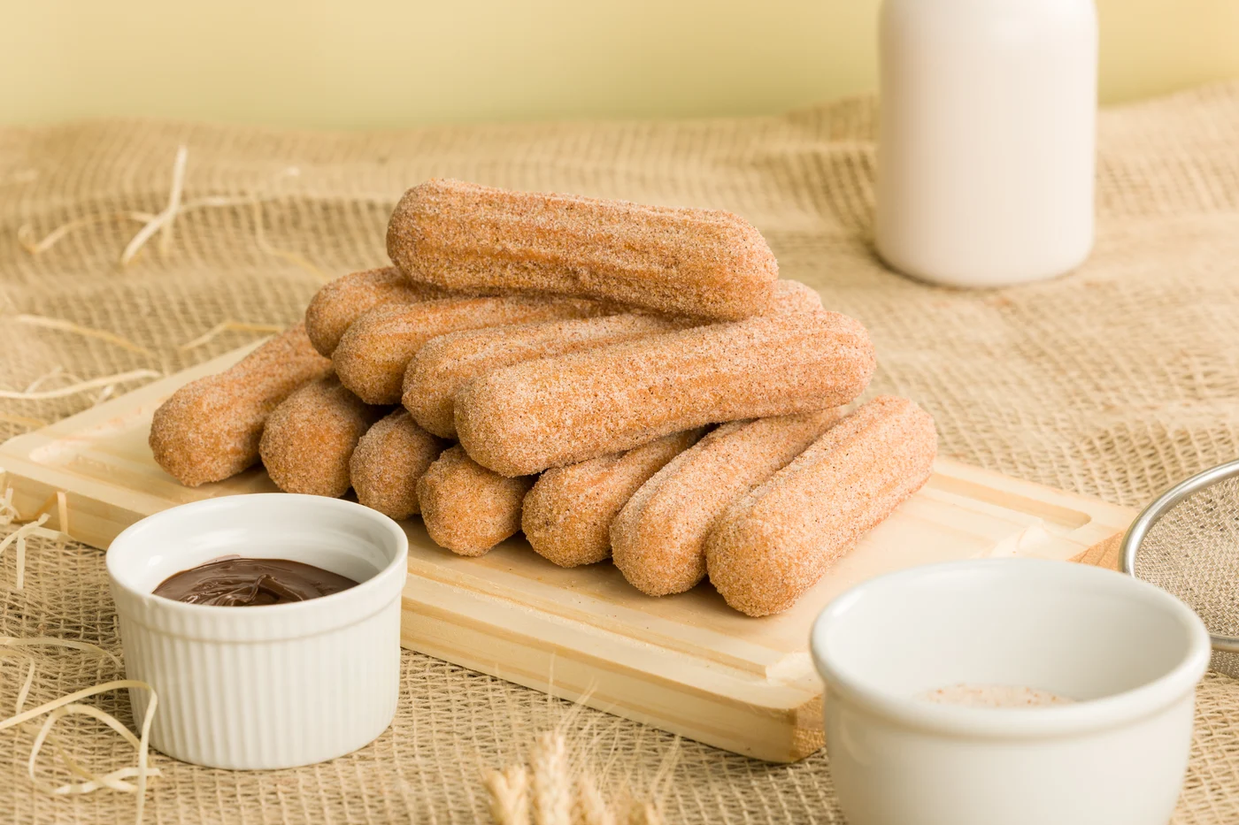Churros com açúcar e canela, acompanhados de uma xícara