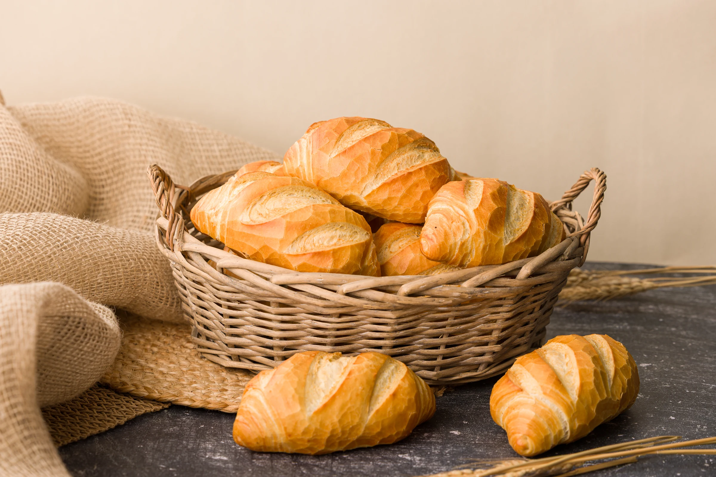 Cesta de pães franceses dourados sobre tecido rústico